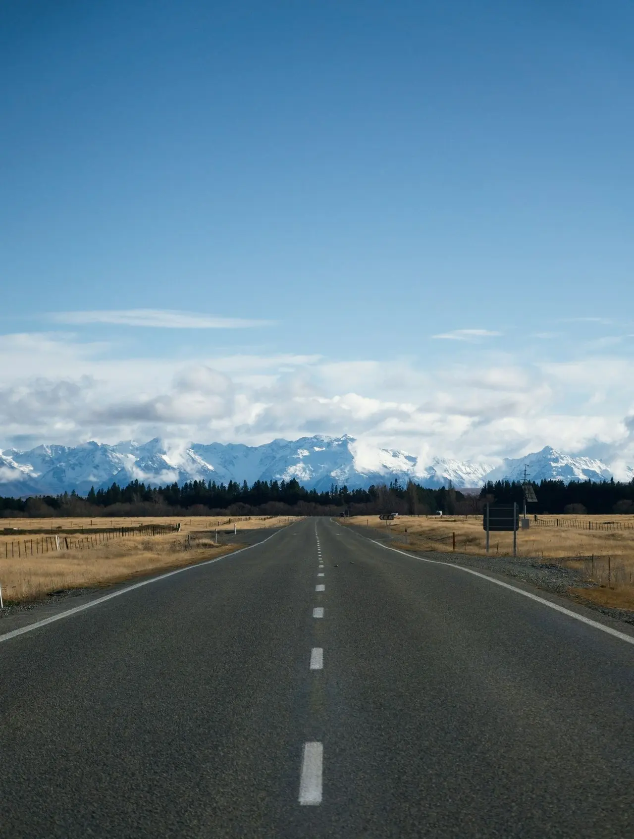a long empty road with mountains in the background