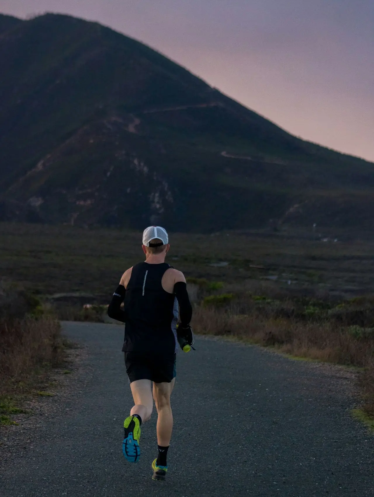 woman jogging on gray road across mountain during daytime